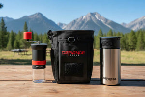 Defiance Tools pouch with a coffee grinder and insulated french press in front of mountain scenery